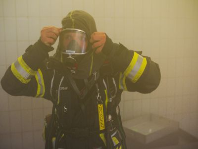 Feuerwehrmann in Schutzkleidung mit Atemschutzmaske in verrauchten Innenräumen