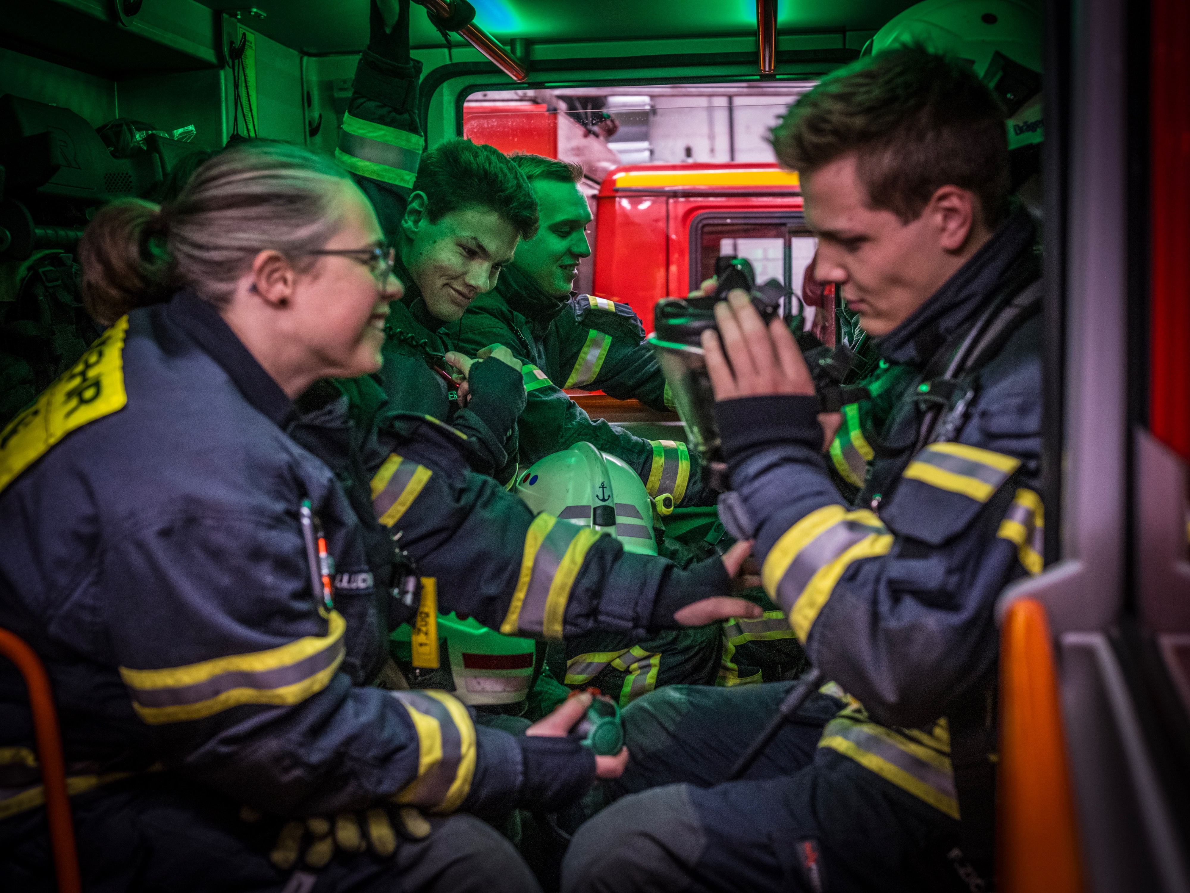Feuerwehrleute in Einsatzkleidung sitzen in einem Fahrzeug, einer hält ein Atemschutzmaske in der Hand